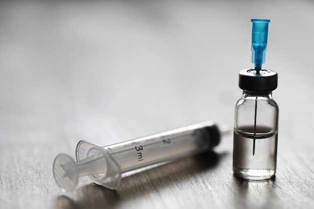 Ampoule and needles from a medical syringe on wooden background