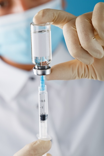 Ampoule and syringe in the hands of a researcher doctor in rubber gloves with a vaccine close-up and