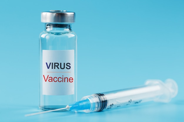 Ампула и шприц с вакциной против вируса против болезней на синем фоне.