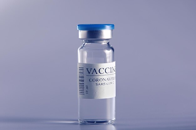 ampoule with Covid19 vaccine in laboratory to fight the coronavirus sarscov2 pandemic Glass vial medical closeup isolated on a blue background