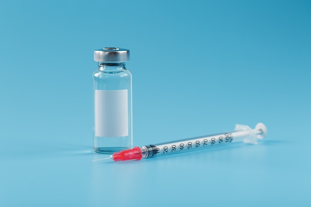 Ampoule with a vaccine and a syringe for viruses and diseases on a blue background.