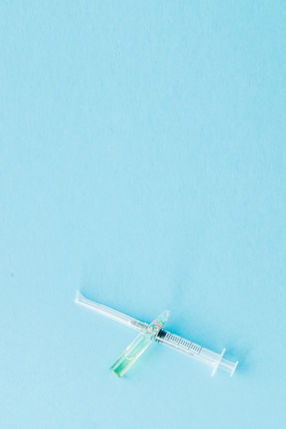 Ampoules and syringes close up on blue wall. Copy space