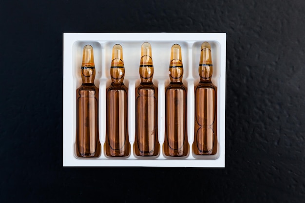 Photo ampoules with medicine in packaging on a black background