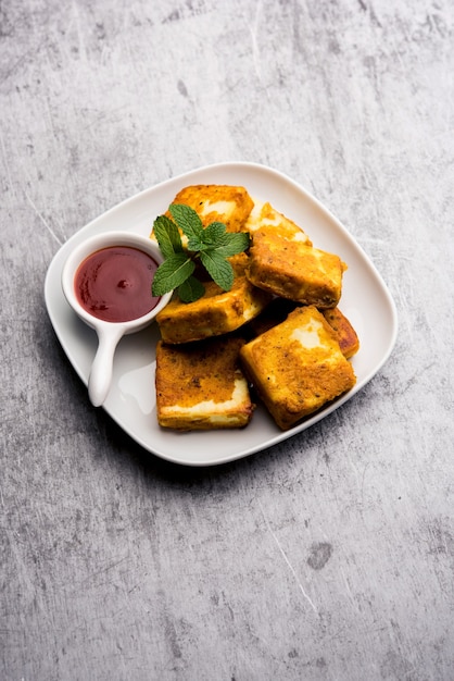 Amritsari Paneer Tikka gemaakt met blokjes kwark gedoopt in een beslag gemaakt met besan, chat masala en kruiden en ondiep gebakken in de pan, geserveerd met ketchup