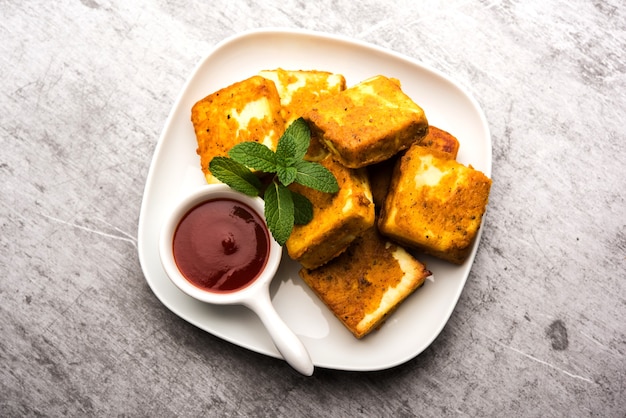 Amritsari Paneer Tikka gemaakt met blokjes kwark gedoopt in een beslag gemaakt met besan, chat masala en kruiden en ondiep gebakken in de pan, geserveerd met ketchup