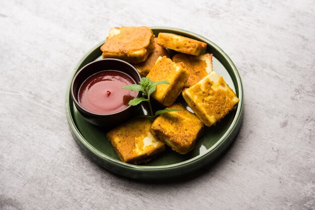 Amritsari Paneer Tikka made using cottage cheese cubes dipped in a batter made with besan, chat masala and spices and shallow fried in pan, served with ketchup