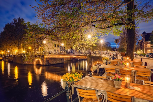 Amsterdam cafe tables canal bridge and medieval houses in the e
