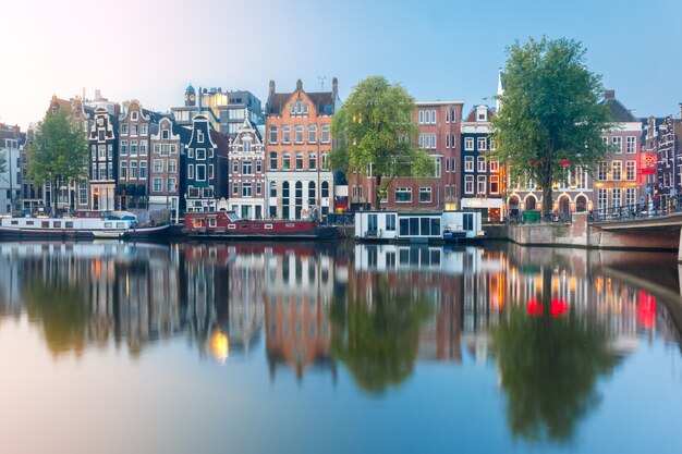 Amsterdam canal Amstel with typical dutch houses and boats during sunrise, Holland, Netherlands.