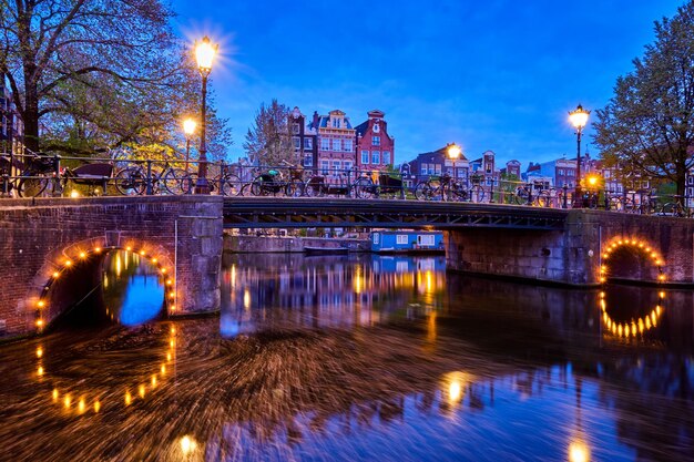 Photo amsterdam canal bridge and medieval houses in the evening