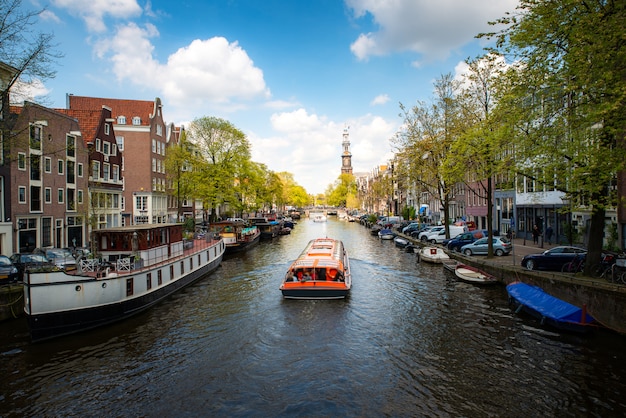 Amsterdam canal with cruise ship with Netherlands traditional house in Amsterdam