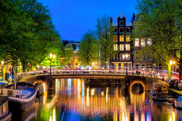 Amsterdam canal with typical dutch houses and bridge during twilight blue hour in holland, netherlands