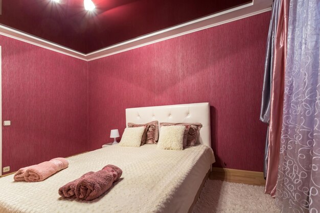 Amsterdam netherlands july 2019 double bed with pillows in\
interior of the modern intimate bedroom in flat in pink color style\
apartments