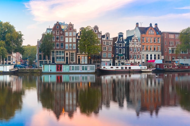 Amsterdamse gracht Amstel met typisch Nederlandse huizen en boten tijdens zonsopgang, Holland, Nederland.