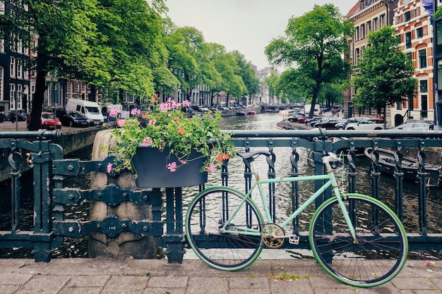 Amsterdamse gracht met boten en fietsen op een brug