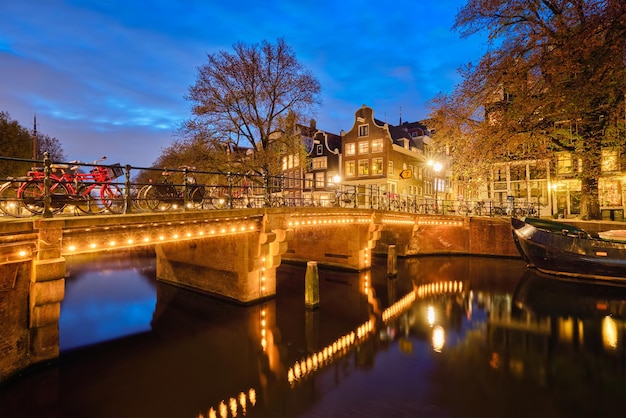 Amsterdamse kanaalbrug en middeleeuwse huizen in de avond