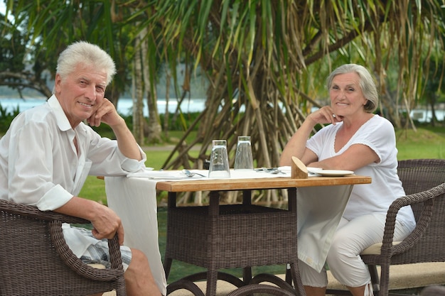 Amusant gelukkig lachend oud stel aan cafétafel