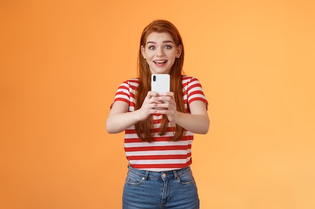 Photo amused excited redhead female record video thrilled see famous person smiling amazed hold smartphone...