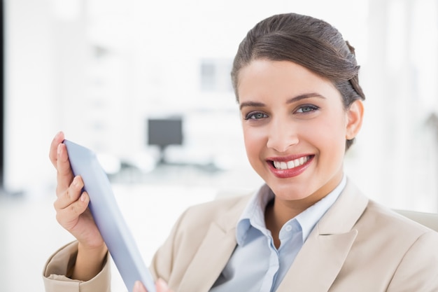 Amused smart brown haired businesswoman using a tablet pc