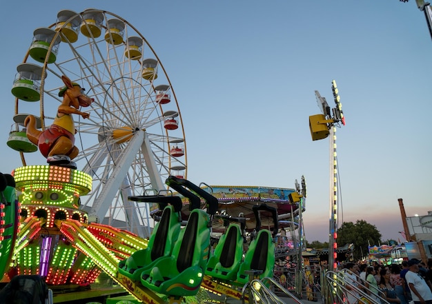 Amusement park at sunset full of color and with rotating attractions such as a vintage Ferris wheel