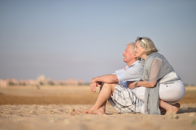 Amusing elderly couple went to the beach to enjoy the sea breeze