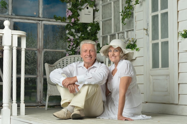 Amusing happy smiling old couple posing near house