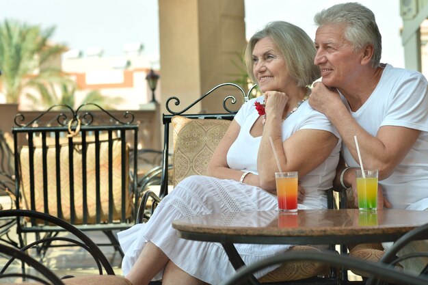 Amusing old couple on vacation drinking cocktail