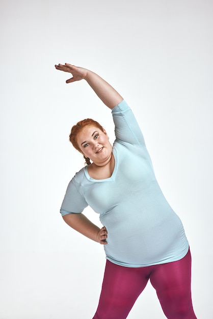 Amusing red haired chubby woman is doing exersizes