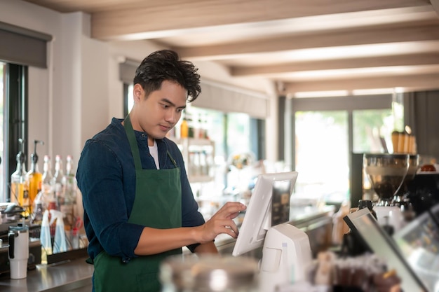 Фото Азиатский мужчина-предприниматель или бариста, работающий в современном концептуальном малом бизнесе кафе