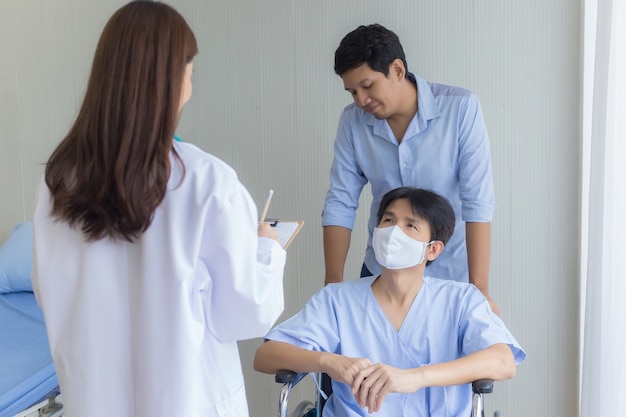 아시아 여성 의사가 병원에서 그의 증상에 대해 남성 환자와 확인하고 이야기하고 있다