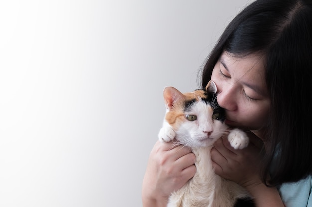 写真 猫に優しくキスするアジア人女性。