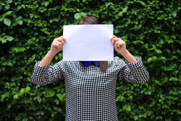 Фото Азиатская женщина стоит с белой бумагой на лице. может разместить текст для рекламных носителей.