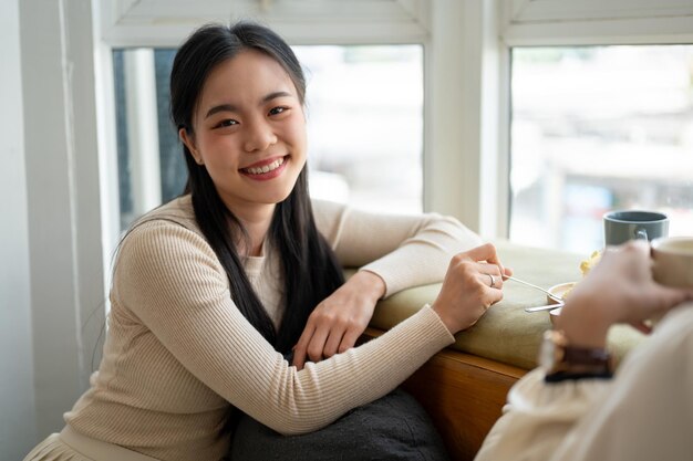 사진 매력적인 아시아 여성이 주말에 친구와 함께 아름다운 카페에 앉아 즐거운 시간을 보내고 있습니다.