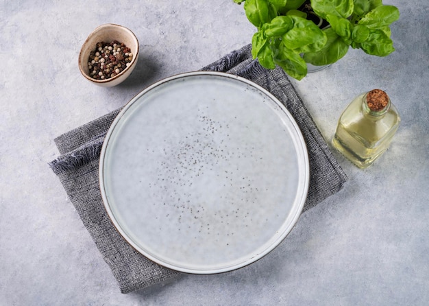 Фото Пустая керамическая тарелка на синем фоне с масляными специями и свежим базиликом концепция здорового питания