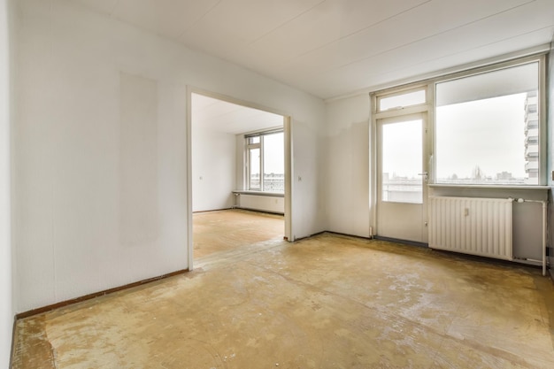 Фото Пустая просторная комната с большими окнами и белыми стенами в квартире жилого дома