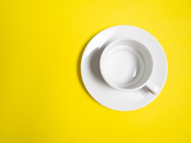 Фото Пустая белая чашка и блюдце на желтом фоне, копия пространства