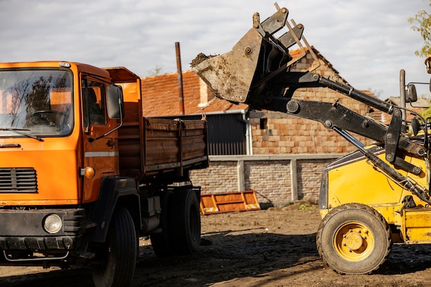 Фото Экскаватор наполняет грузовик грунтом на проселочной дороге