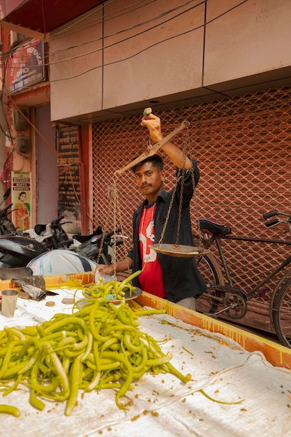 写真 古い秤で野菜と豆の重さを量るインド人の売り手