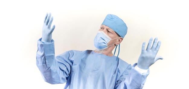 写真 青い防護服を着た感染症の医師が、保護用のゴム手袋をはめた自分の手を注意深く調べています