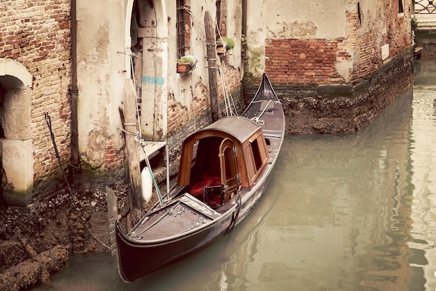 Фото Старая гондола на венецианском канале, пришвартованная к узкому выходу из улицы
