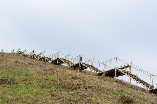 Фото Старая высокая деревянная лестница поднимается на большую гору. лестница символизирует рост, восхождение, стремление, силу воли. тетюши, татарстан.