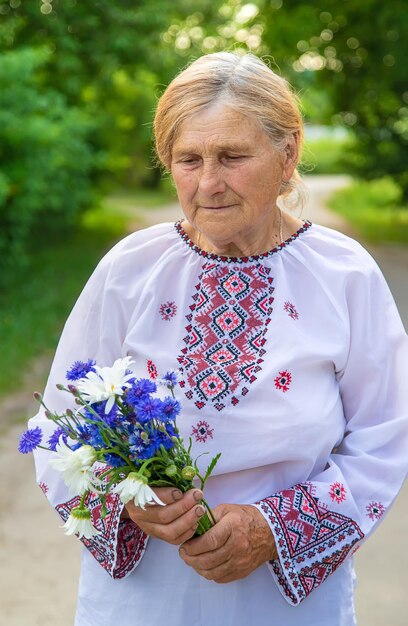 Фото Пожилая украинка в вышиванке с букетом цветов селективный фокус