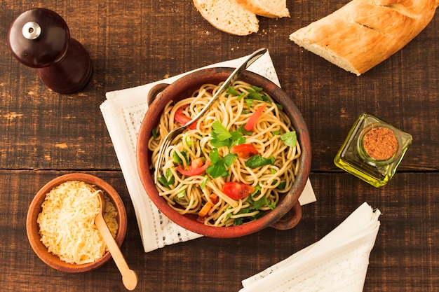 Фото Верхний вид спагетти-пасты с сыром и хлебом на деревянном столе