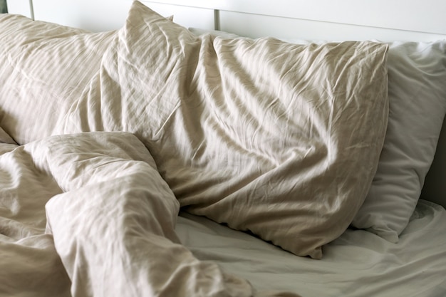 写真 寝た後の朝の枕、シーツ、毛布付きの整えられていないベッド、側面図