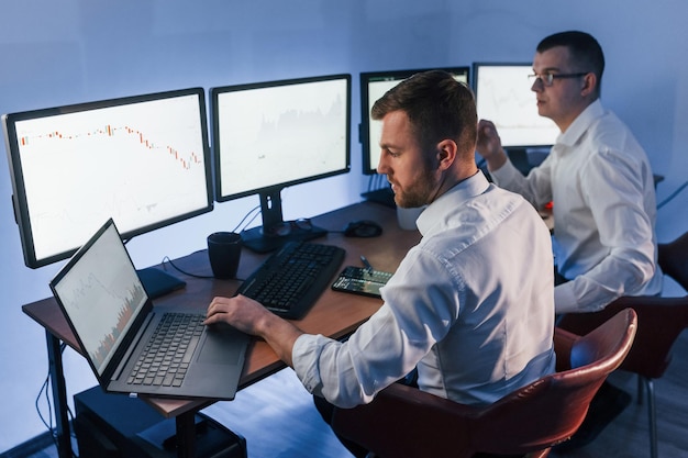 Analizing graphs together Two stock traders working in the office with exchange technology