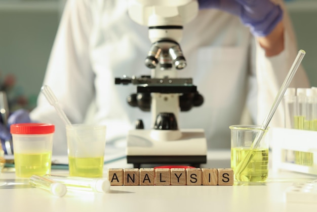 Analyse-inscriptie op houten kubussen close-upmicroscoop en urinemonsters op de tafel in de