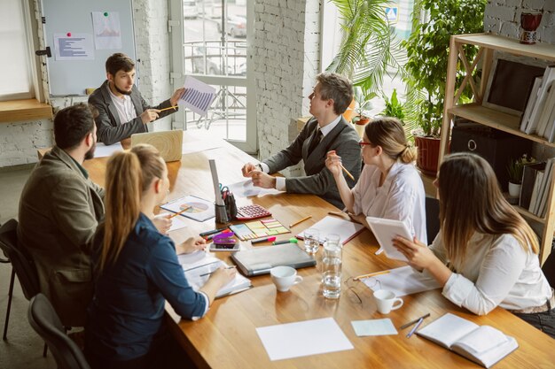 Analysis. Group of young business professionals having a meeting. Diverse group of coworkers discuss new decisions, plans, results, strategy. Creativity, workplace, business, finance, teamwork.