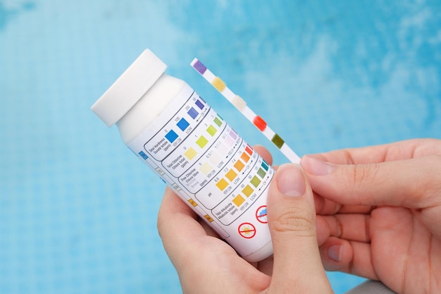 Analysis of the ph and chlorine of the water in a swimming pool in summer check quality of water with test strip comparing results