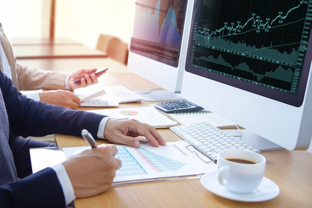 analysts or businessmen in front of modern computer screens reviewing graphs and financial reports for stock trading or return on investment.