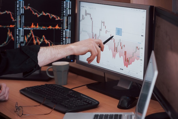 Analisi dei dati primo piano di giovane uomo d'affari che indica sui dati presentati nel grafico con la penna mentre lavorando nell'ufficio creativo