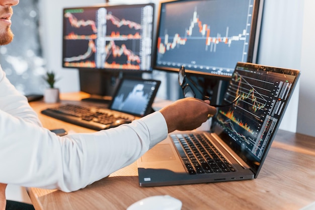 Analyzing information Young businessman in formal clothes is in office with multiple screens